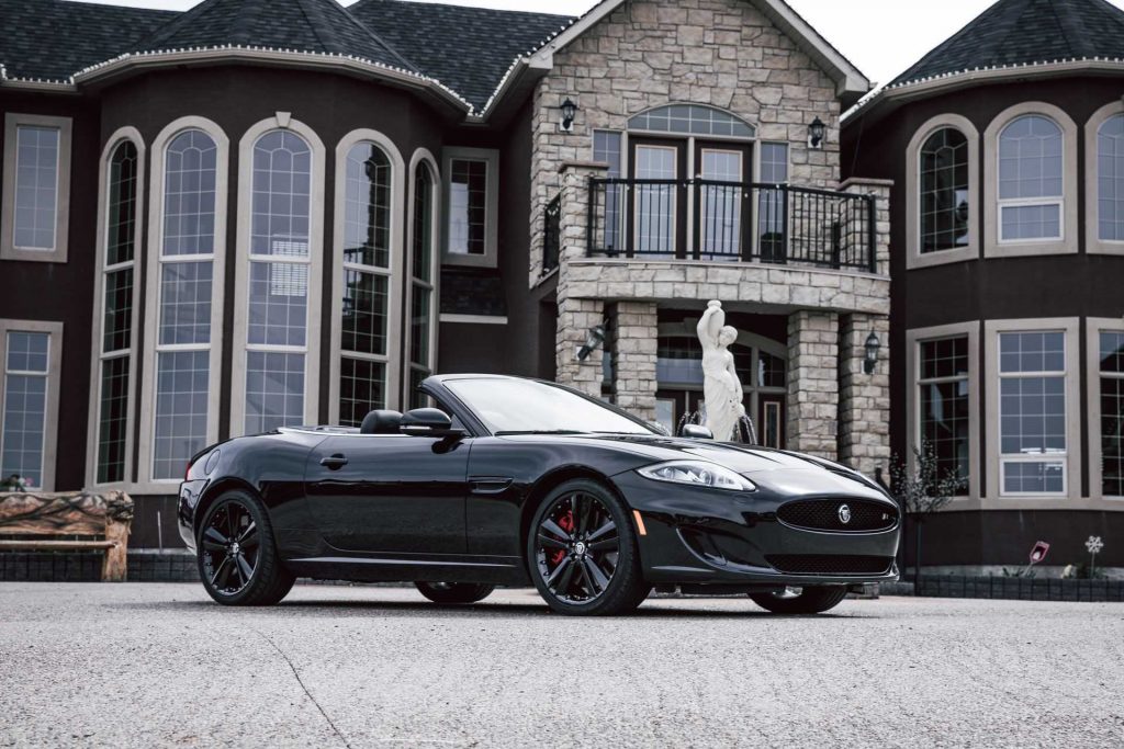 expensive mansion with a convertible in the driveway