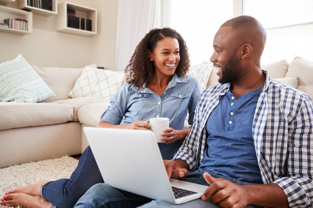 couple smiling at computer because they have money saved

