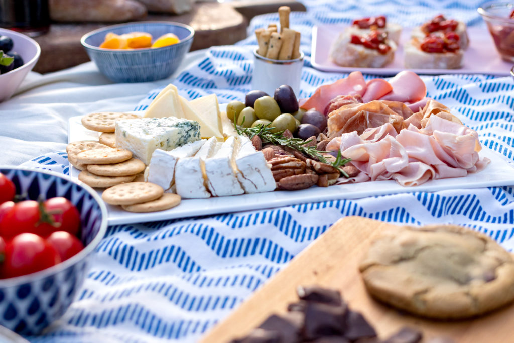 Cheese, and meat board on a picnic blanket
